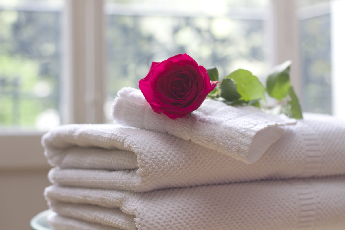 A stack of towels with a red rose on top